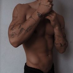 a shirtless man with tattoos on his arms and chest standing in front of a wall