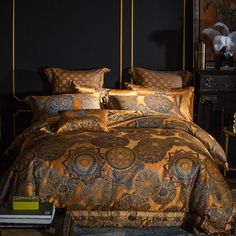 a bed with gold and blue comforters in a dark room next to a night stand