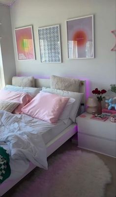 a white bed with pink pillows and blankets