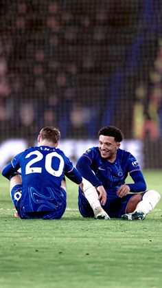 two soccer players sitting on the ground laughing