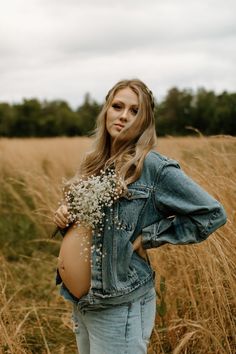 a pregnant woman standing in a field with her hands on her hips