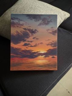 an image of a sunset with clouds in the sky on a couch cushion that is next to a pillow