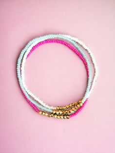 three beaded bracelets on a pink background