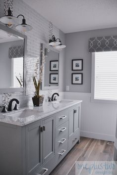 a large bathroom with two sinks, mirrors and pictures on the wall above it's countertop