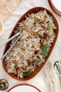 a bowl filled with rice and garnished with green leaves next to silverware