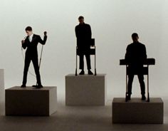 three men in suits are standing on pedestals