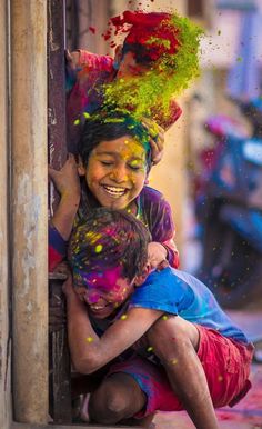 two children are hugging each other while covered in colored powder