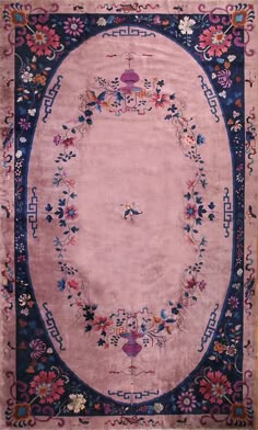 a pink rug with blue border and flowers on it