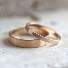 two gold wedding rings sitting on top of each other