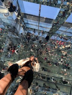 a woman taking a selfie in front of a glass building with lots of people