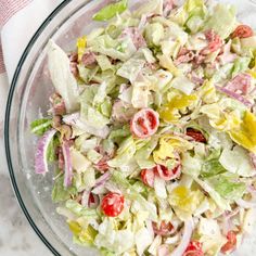 a glass bowl filled with salad on top of a white marble countertop next to a red and white towel