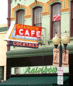 the rainbow cafe sign is hanging on the side of the building in front of it