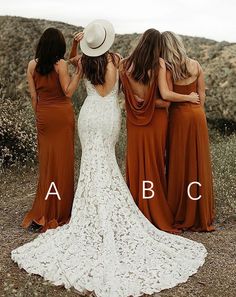 three bridesmaids in dresses and hats standing on the side of a hill with their backs to the camera