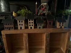 small wooden houses sitting on top of a table next to a candle and potted plant