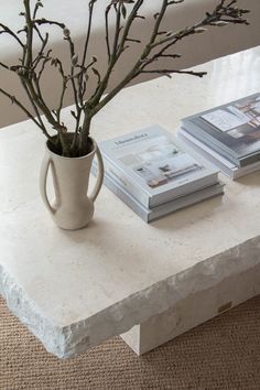 a white table topped with a vase filled with flowers next to two books on top of it