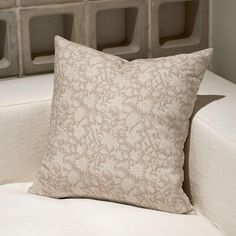 a pillow sitting on top of a white couch next to a wall with storage bins