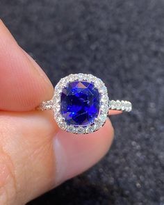 a close up of a person holding a ring with a blue stone in the middle