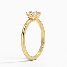 a yellow gold engagement ring with a pear shaped diamond in the center, on a white background