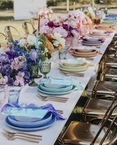 a long table is set with blue and white plates, silverware, and flowers