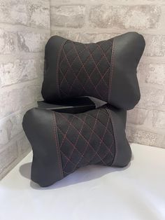 two black leather pillows sitting on top of a white table