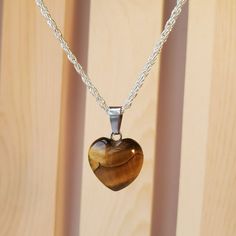 Necklace With Real Polished Stone Pendant On A 18" Silver Metal Chain. The Pendant Is A Polished Gold Tiger's Eye Gemstone In A Heart Shape. Tiger's Eye Is A Beautiful Natural Gemstone Which Glimmers With Gold, Brown And Bronze Highlights. The Pendant Itself Is About 0.5 Inch In Size And Is A Heart Shape. Each Necklace Comes With A Pretty Jewelry Bag To Protect It. This Would Be A Lovely Mother's Day Gift! Tiger's-Eye Gets Its Name Because Of The Reflections Of Light Forming Bands Across The Sto Tigers Eye Crystal Necklace, Gemstone Stainless Steel Necklace For Gift, Nickel-free Stainless Steel Heart Pendant Jewelry, Double Heart Silver Stainless Steel Necklace, Silver Heart Charm Crystal Necklace For Valentine's Day, Silver Heart-shaped Stainless Steel Necklace, Silver Heart Stainless Steel Necklace, Nickel-free Double Heart Stainless Steel Jewelry, Heart-shaped Stainless Steel Jewelry With Silver Chain