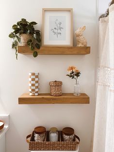 two wooden shelves above a toilet with baskets and flowers on them, in a bathroom