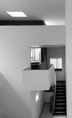 a black and white photo of a staircase in a building with light coming through the windows