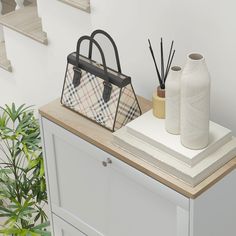 a white cabinet with two vases and a handbag on it, next to a plant