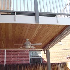 a ceiling fan is mounted to the side of a house's wooden porch roof