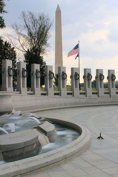 the washington monument is surrounded by water fountains and an american flag flying in the background