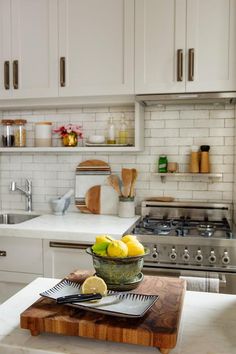 a bowl of lemons sitting on top of a cutting board next to a stove