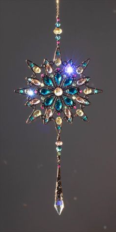 a snowflake ornament hanging from a chain with lights in the middle