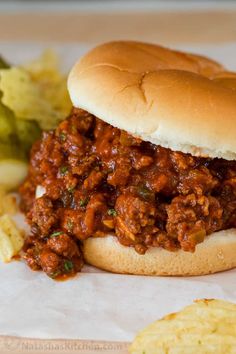 a sloppy joe sandwich sitting on top of a bun next to some potato wedges