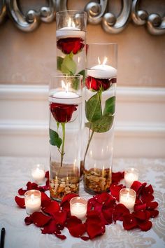 three vases filled with flowers and lit candles