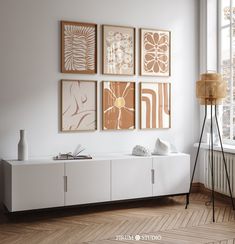 a living room with white furniture and paintings on the wall