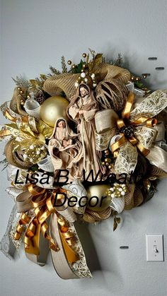 a christmas wreath hanging on the wall next to a light switch with an image of mary and jesus