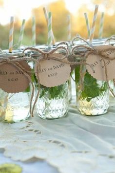 four mason jars filled with green leafy leaves and twine tags are sitting on a table