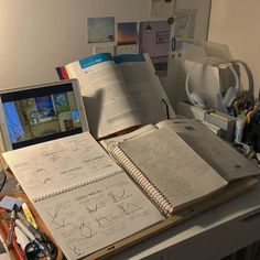 an open laptop computer sitting on top of a desk next to a bunch of papers