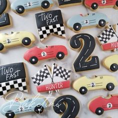 decorated cookies with race cars and numbers are displayed on a white tablecloth for a two - year birthday party