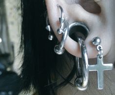 a close up of a person wearing ear piercings with a cross on the side