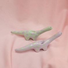 two green and white plastic dinosaurs on a pink background