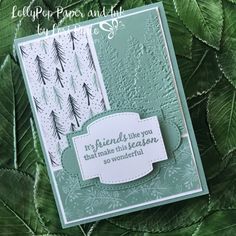 a close up of a card with green leaves and snowflakes in the background