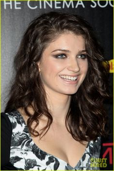 a woman with long hair smiling at the camera and wearing a black and white dress