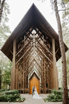 a bride and groom standing in front of a large wooden structure at the end of their wedding day