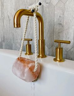 a rope hanging from the side of a bathtub next to two faucets