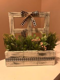 an old window frame is decorated with plants and greenery for the centerpieces