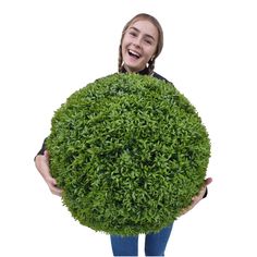 a woman holding a large round bush in front of her face and smiling at the camera