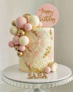 a birthday cake decorated with pink, gold and white decorations on top of a table