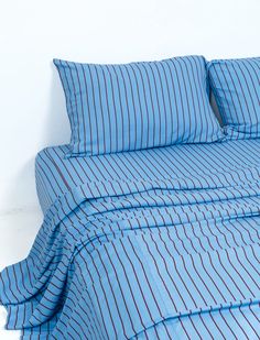 a bed with blue and red striped comforter on it's side next to a white wall