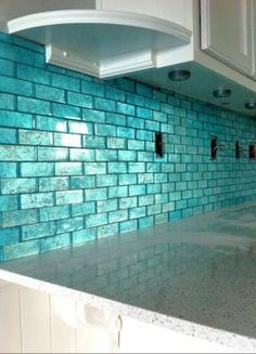 a kitchen with blue tiles on the backsplash and white cabinets in front of it